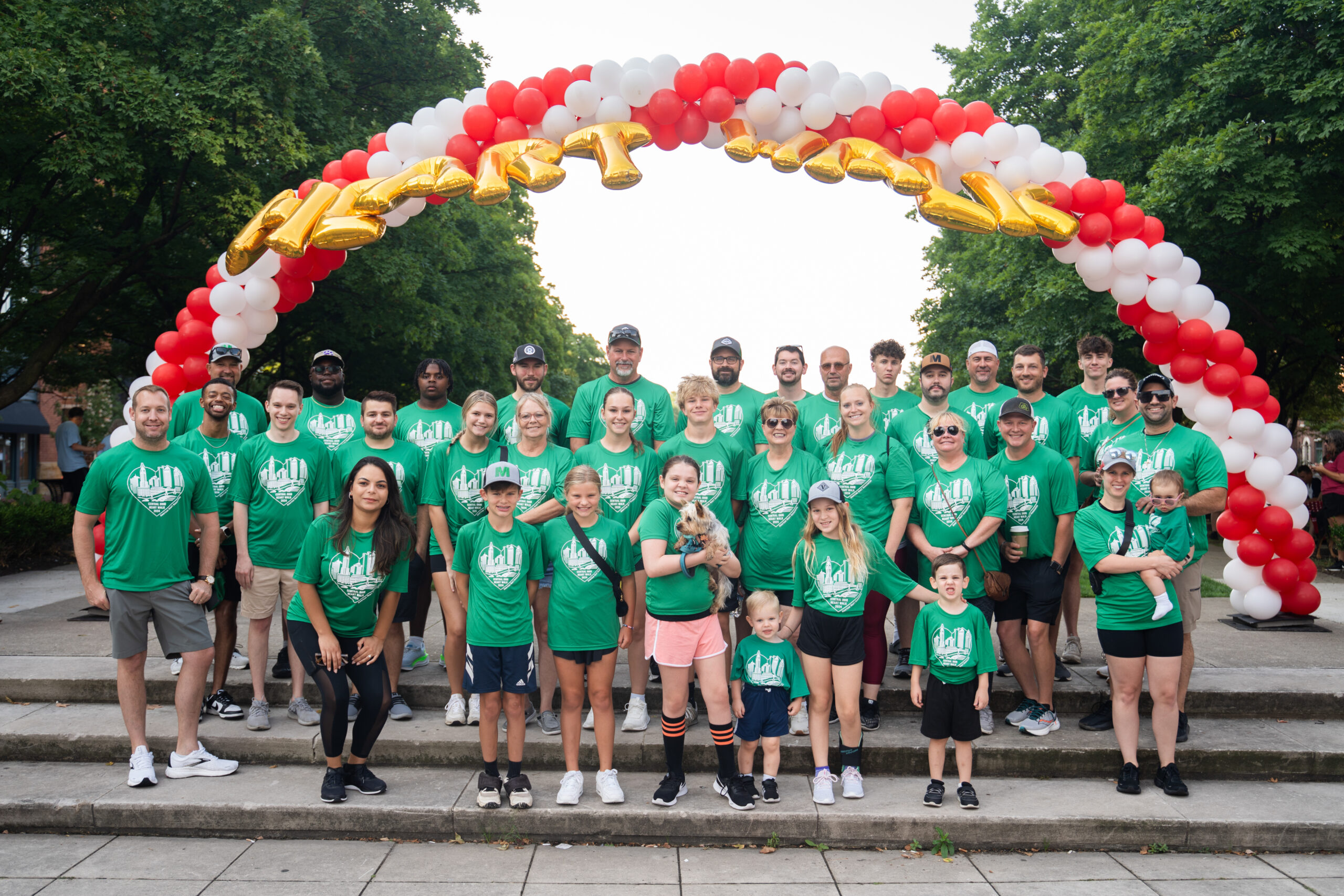 Messer Construction Company employees in Columbus wearing matching green shirts in a group under a balloon arch